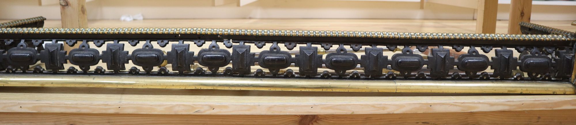A Victorian brass and cast iron pierced fender and a three-piece set of later fire irons